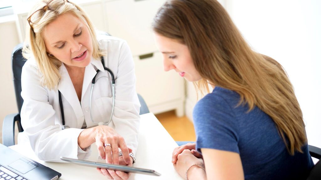 woman talking with doctor while looking at document